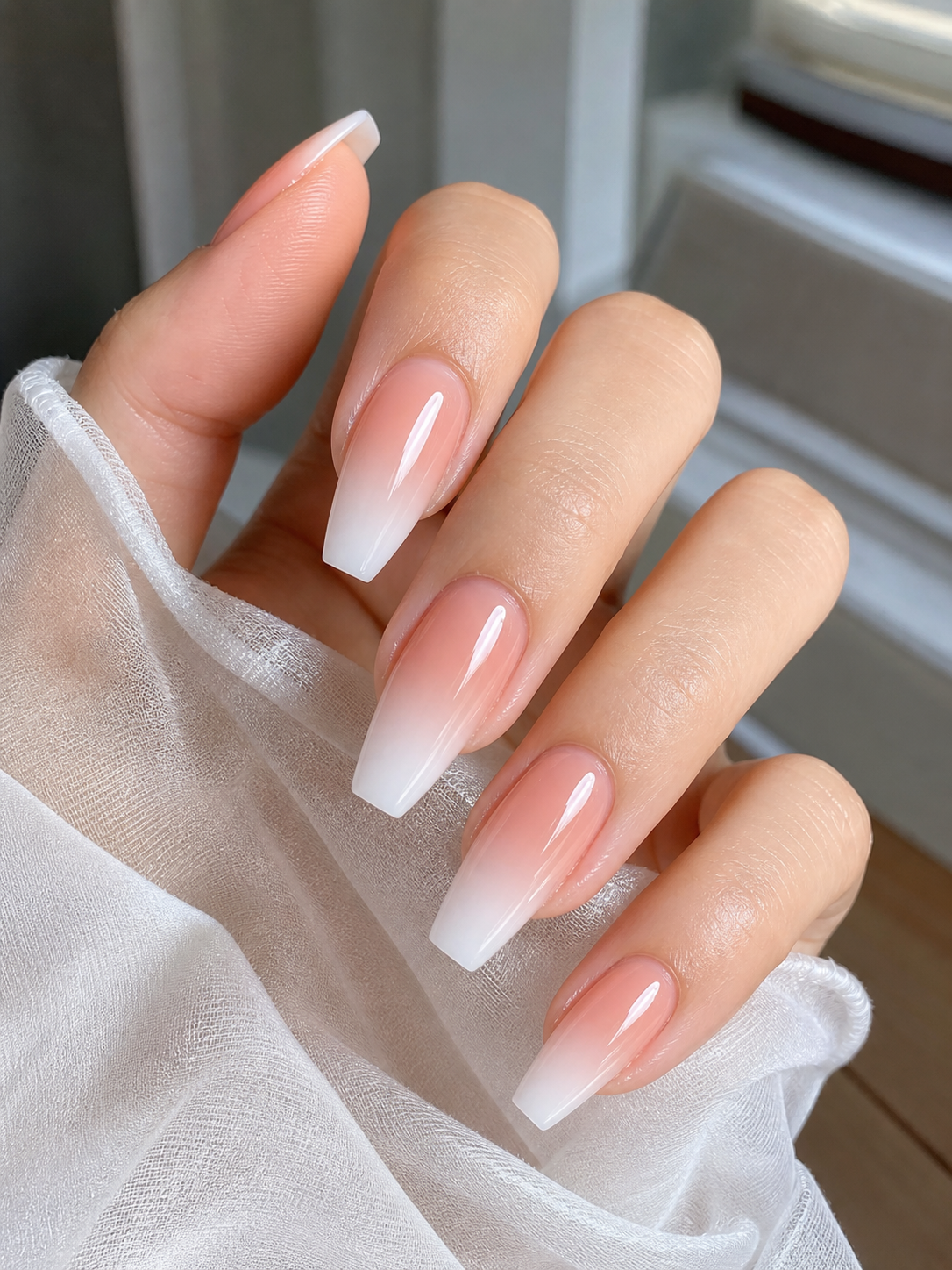 Ongles de longueur moyenne en forme coffin avec un dégradé ombré pêche translucide vers blanc laiteux et finition brillante.